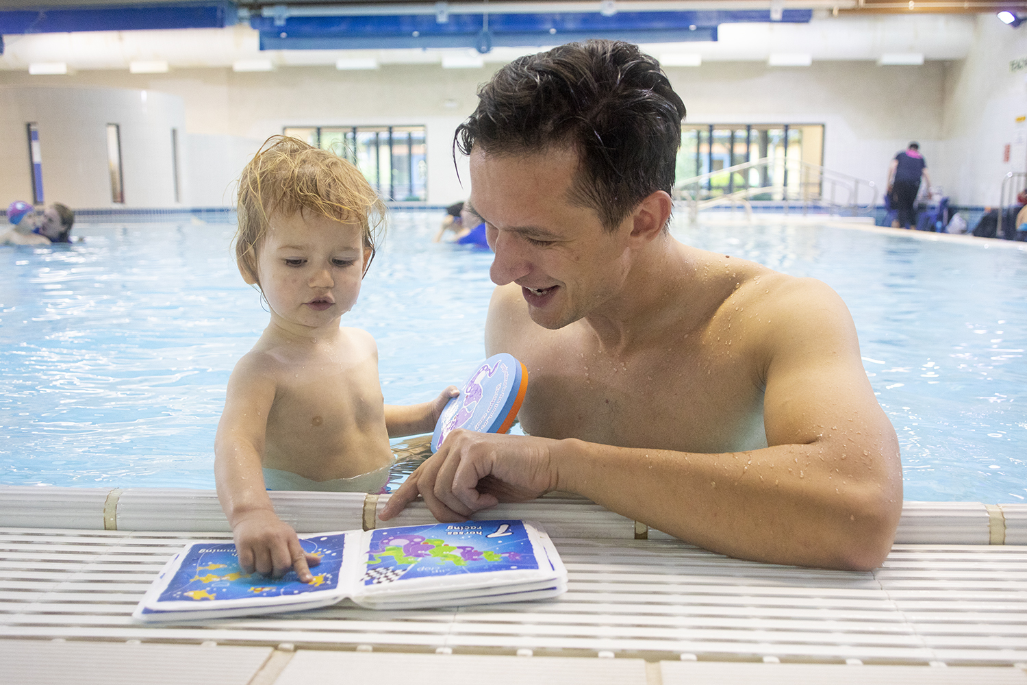 toddler and dad reading in the pool
