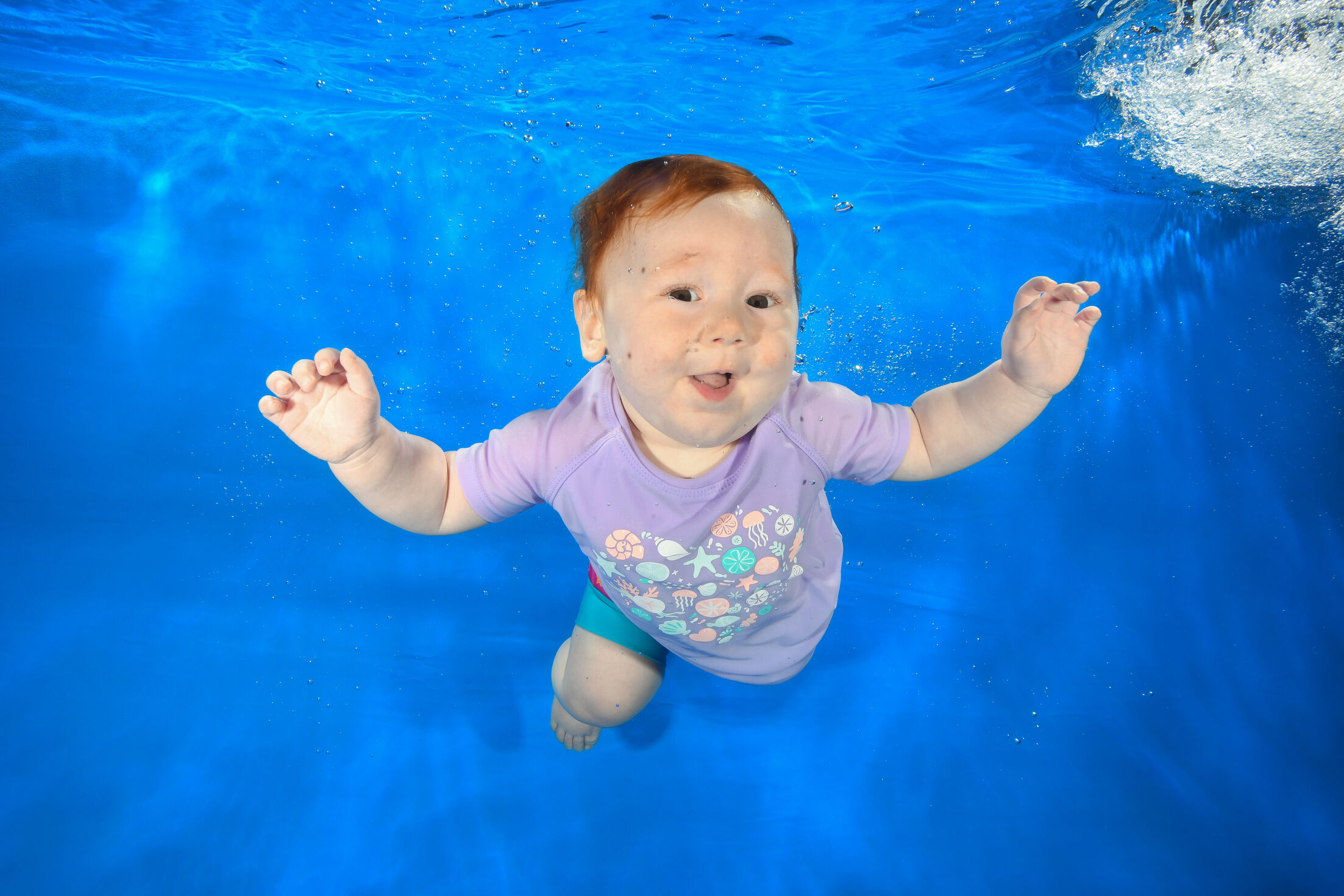 Cute little girl swimming and posing at underwater photoshoot