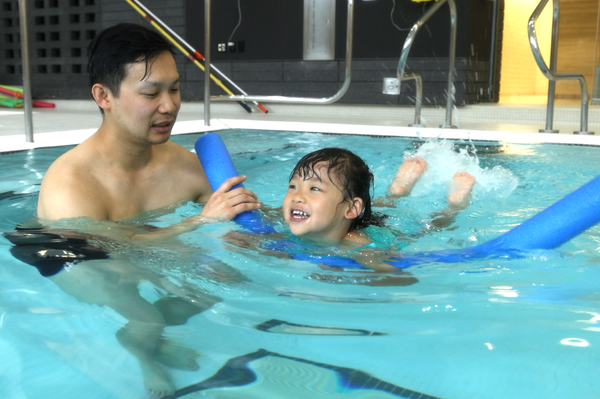 Ingrid and her dad in the pool having a swimming lesson with a pool noodle