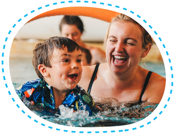 Toddler in the pool with having a swimming lesson with his mum